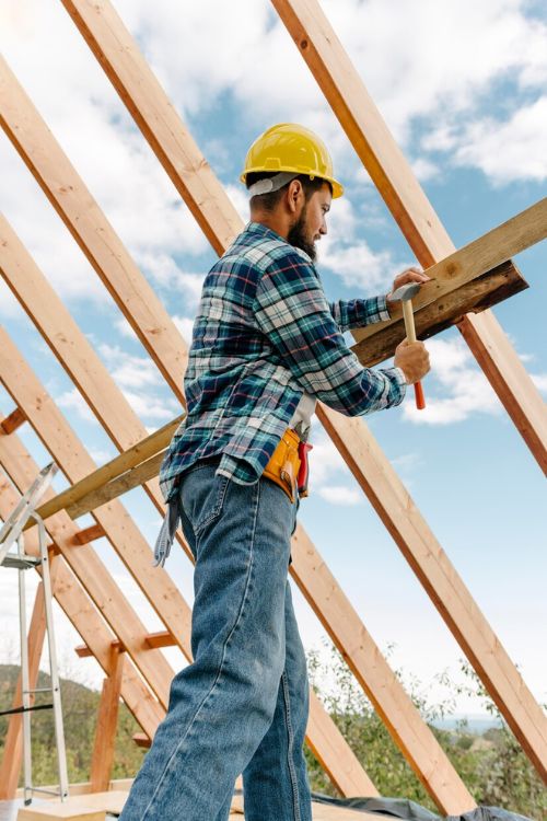 A man is actively constructing a wooden frame on a roof, highlighting a roofing service in Naperville.