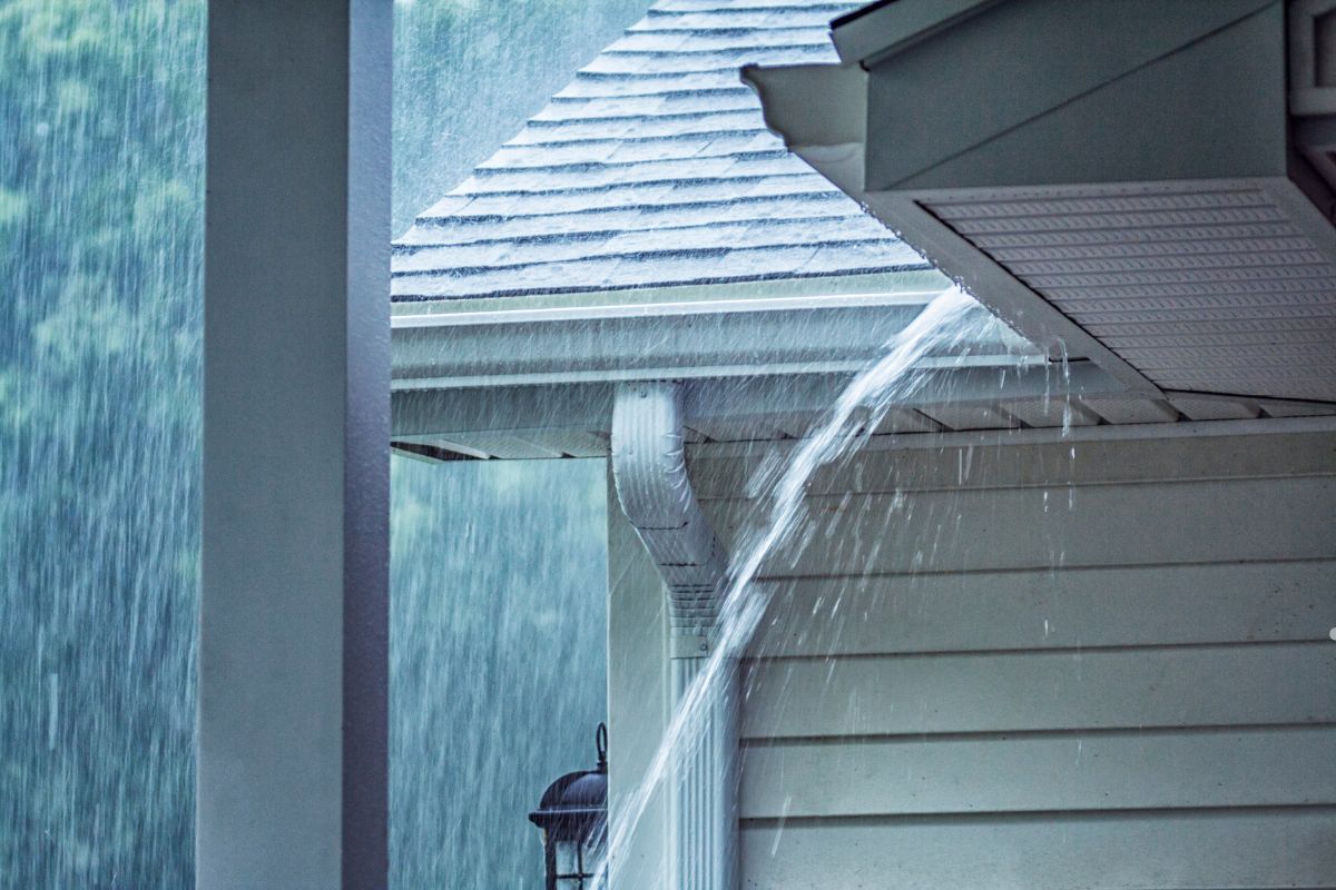 A house with water cascading from the roof, illustrating the effects of pre-storm roofing conditions.